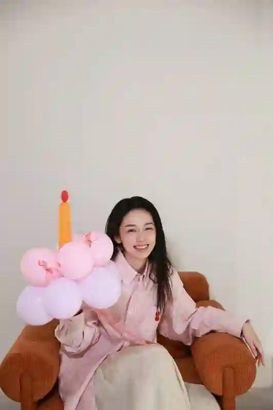 周也身着粉色条纹衬衫，头戴气球宛如梦幻少女