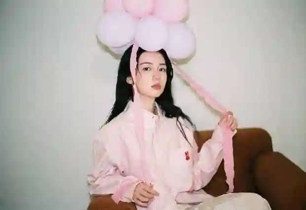 周也身着粉色条纹衬衫，头戴气球宛如梦幻少女