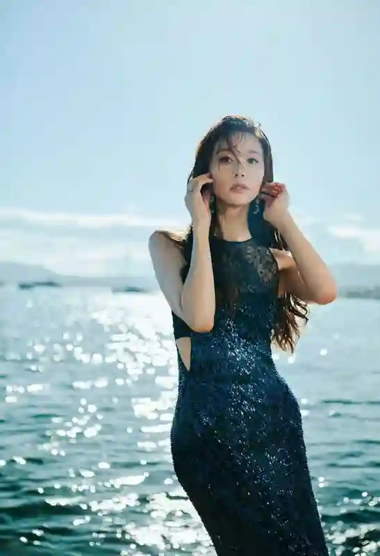 林志玲身着蓝色亮片裙躺卧礁石，如美人鱼般演绎秘境中的温柔诱惑