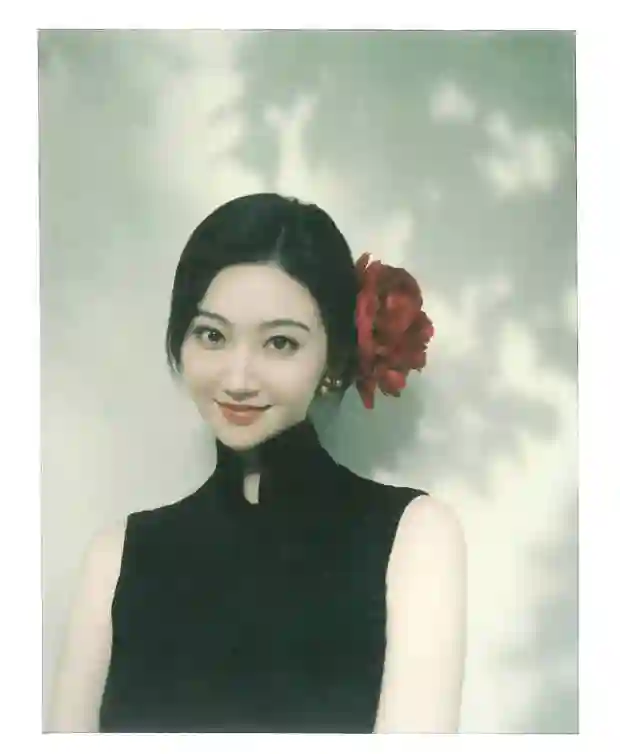 景甜黑色无袖旗袍裙撕拉片，头戴大红花演绎复古明艳风