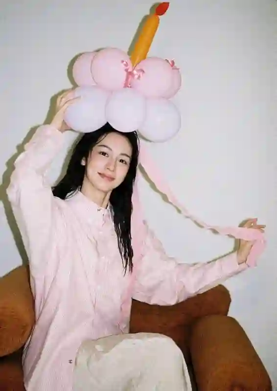 周也身着粉色条纹衬衫，头戴气球宛如梦幻少女