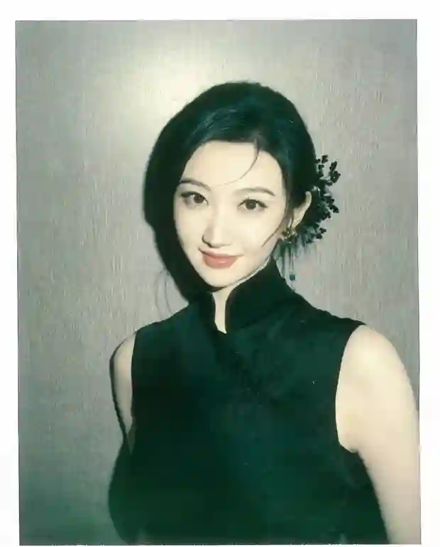 景甜黑色无袖旗袍裙撕拉片，头戴大红花演绎复古明艳风