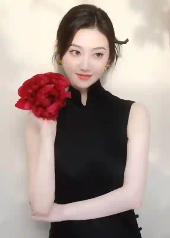 景甜黑色无袖旗袍裙撕拉片，头戴大红花演绎复古明艳风