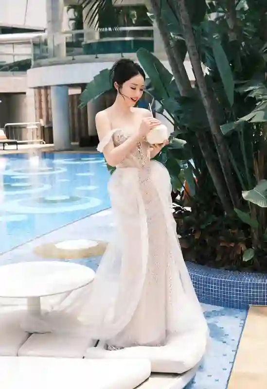 董璇泳池畔饮椰水笑容灿烂，一袭礼裙勾勒曼妙身姿尽显惬意