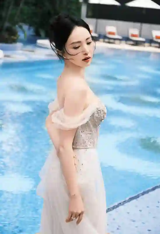 董璇泳池畔饮椰水笑容灿烂，一袭礼裙勾勒曼妙身姿尽显惬意